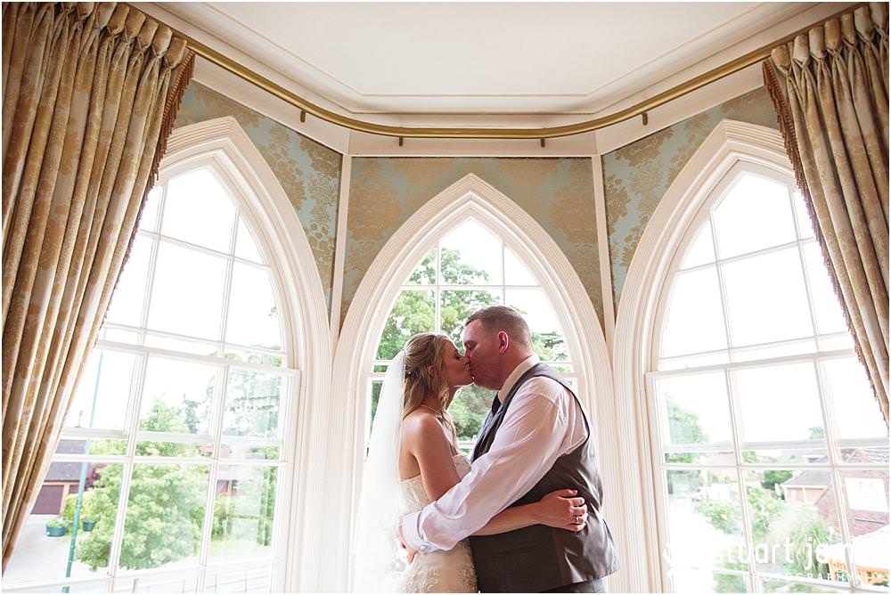 Utilising the stunning windows at Warwick House in Southam for creative evening portraits with the bride and groom captured by Documentary Wedding Photographer Stuart James