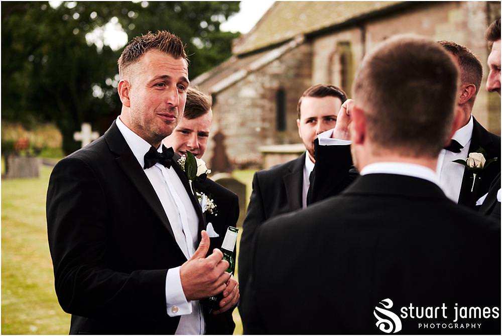 Candid photographs of the groomsmen greeting the guests at St James Church in Acton Trussell by Documentary Wedding Photographer Stuart James