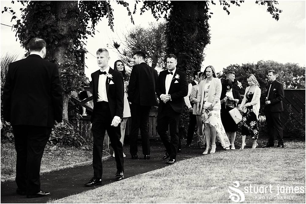 Candid photographs of the groomsmen greeting the guests at St James Church in Acton Trussell by Documentary Wedding Photographer Stuart James