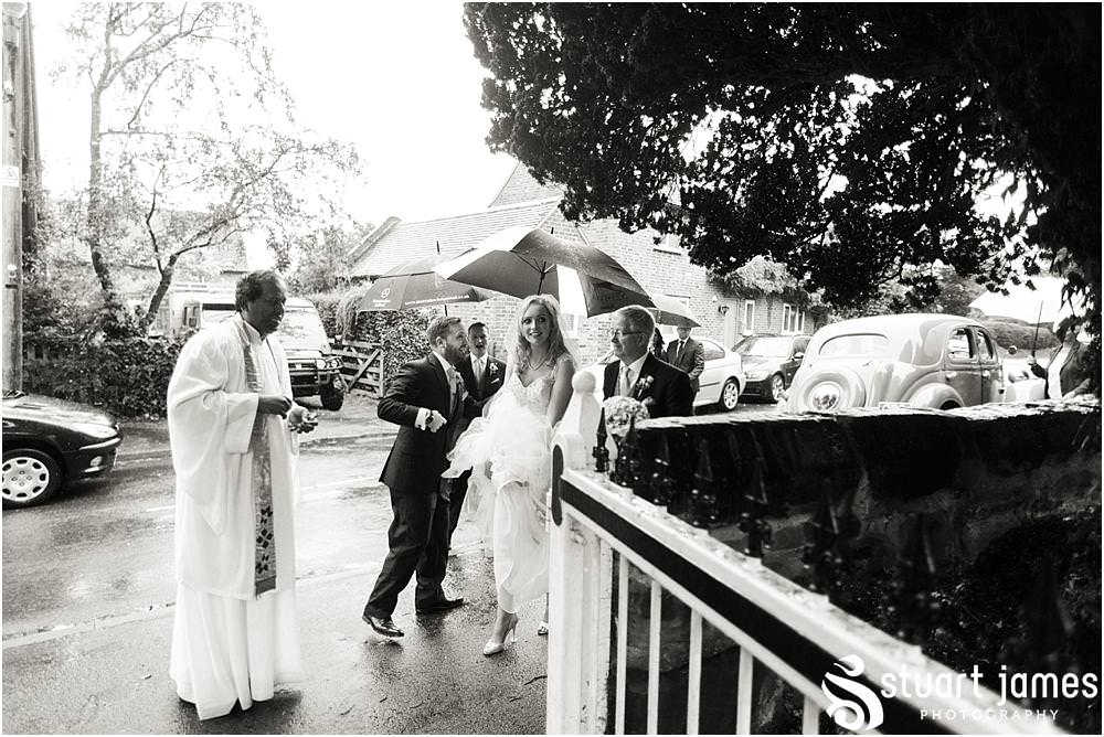 Capturing the arrival of our bride, covered with umbrellas at Middleton Church and Moxhull Hall in Sutton Coldfield by Moxhull Hall Wedding Photographers Stuart James