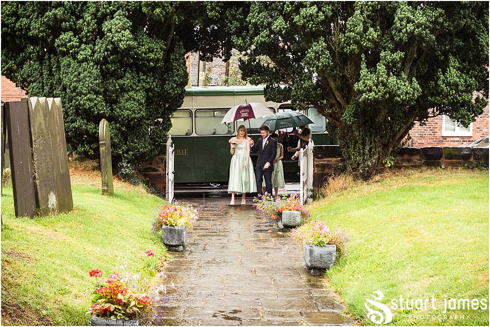An arrival in the rain, but in some fabulous vintage style, for the wedding at Middleton Church and Moxhull Hall in Sutton Coldfield by Moxhull Hall Wedding Photographers Stuart James