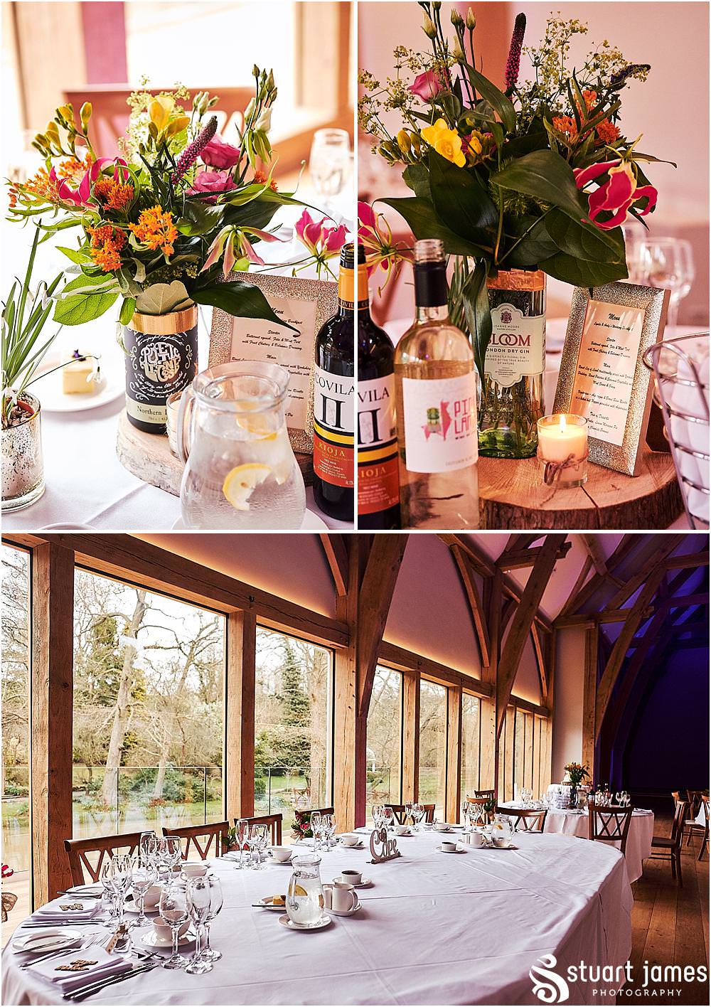 Beautiful floral displays from Lily Jones complimenting the Gin bottles and log centres for the wedding breakfast in The Mill Barns in Alveley by Mill Barns Wedding Photographers Stuart James