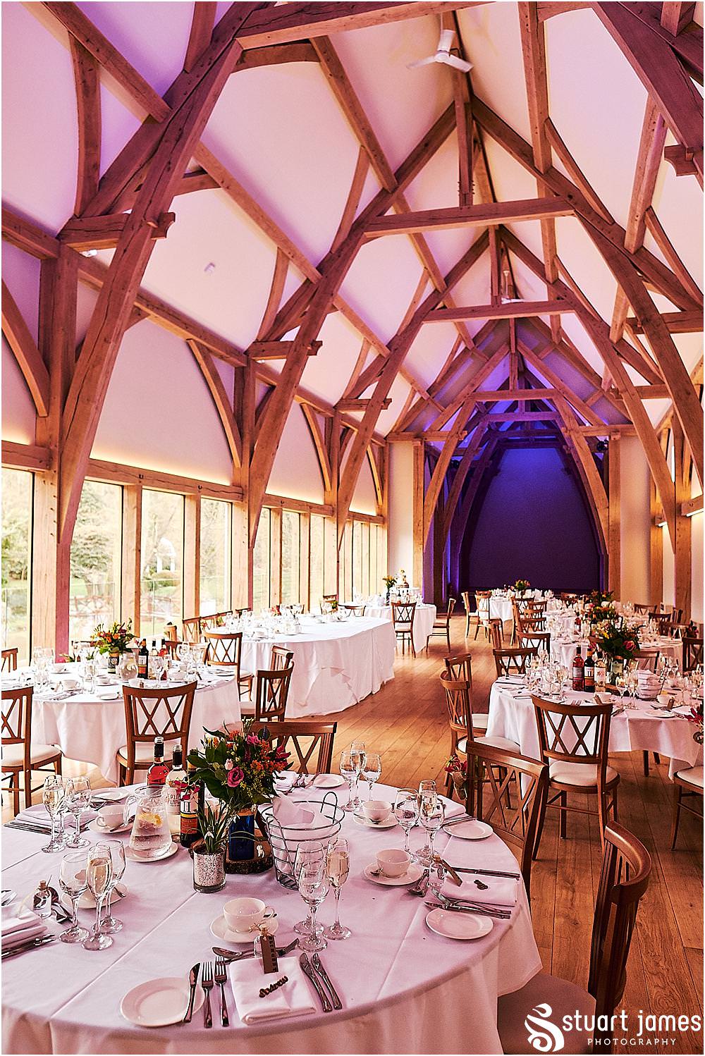 Beautiful floral displays from Lily Jones complimenting the Gin bottles and log centres for the wedding breakfast in The Mill Barns in Alveley by Mill Barns Wedding Photographers Stuart James