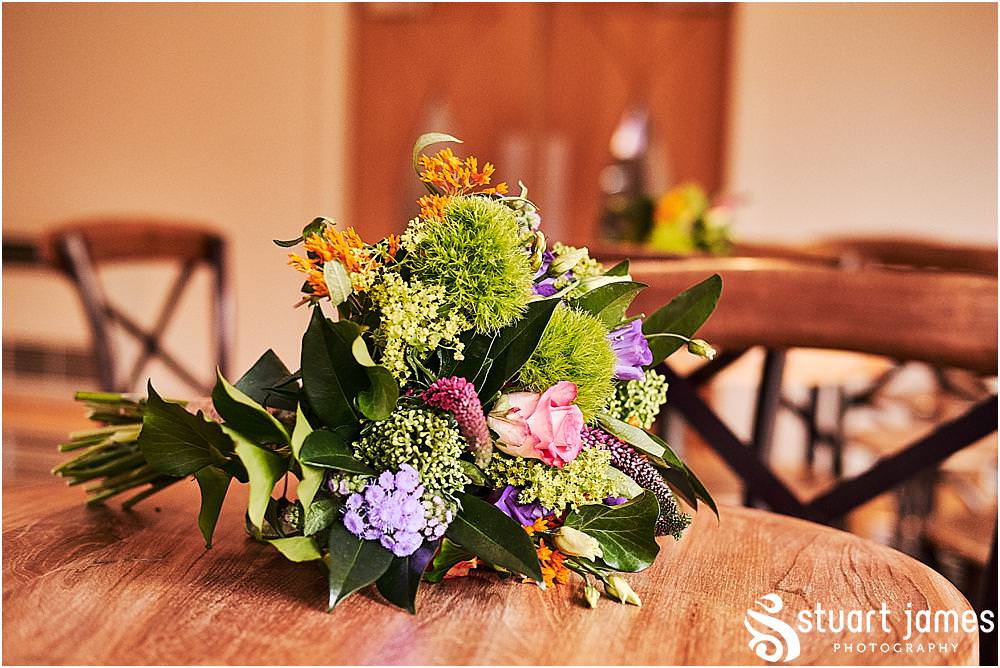 Beautiful floral displays from Lily Jones complimenting the Gin bottles and log centres for the wedding breakfast in The Mill Barns in Alveley by Mill Barns Wedding Photographers Stuart James