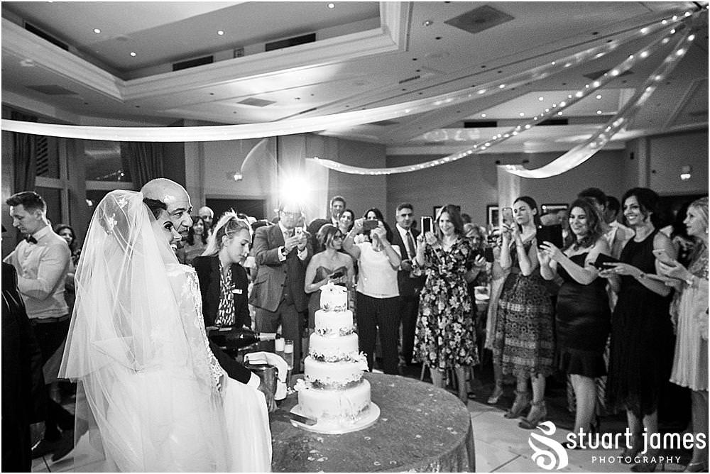Cake cutting fun for the Bride and Groom at The Belfry in Birmingham by Greek Wedding Photographer Birmingham Stuart James