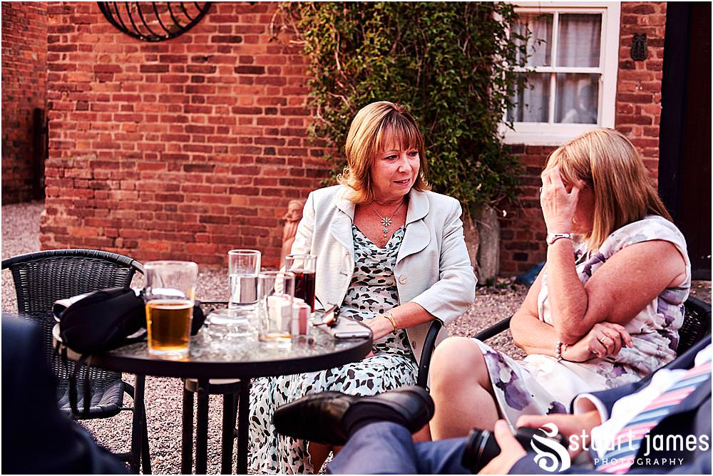 Reportage photos of the guests enjoying the evening sun during the wedding reception at Blakelands in Stourbridge by Documentary Wedding Photographer Stuart James