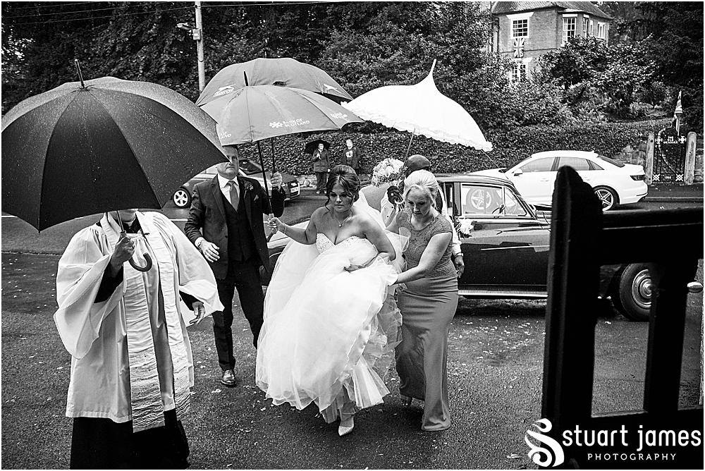 Father and Bridesmaids hold umbrellas over the Bride as she gets out of wedding car, photo by Stuart James Photography at Holy Trinity, Eccleshall