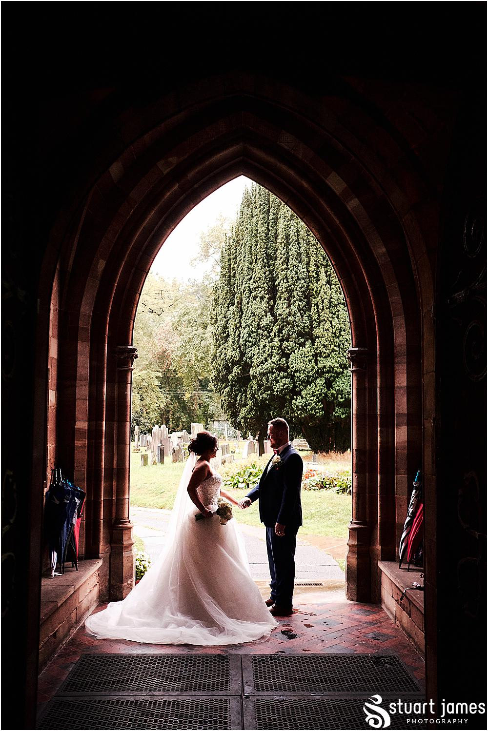 Bride and Groom stand in Chruch arch holding hands, photo by Stuart James Photography at Holy Trinity, Eccleshall