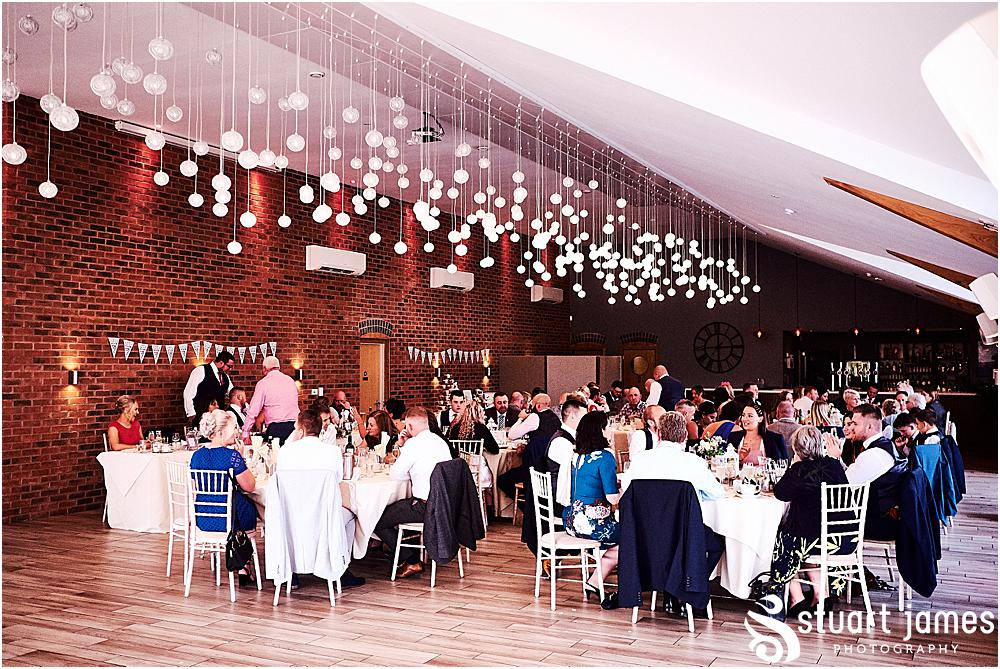 Bride, Groom and Wedding Guests sit down for meal under fairy lights at Aston Marina, photo by Stuart James Photography at Aston Marina, Stone
