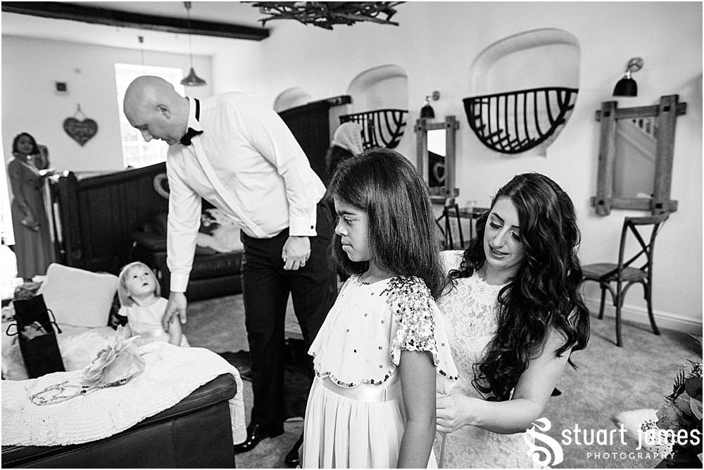 Bride helps dress flower girl in dressing room at Davenport House in Shropshire by Davenport House Wedding Photographers Stuart James