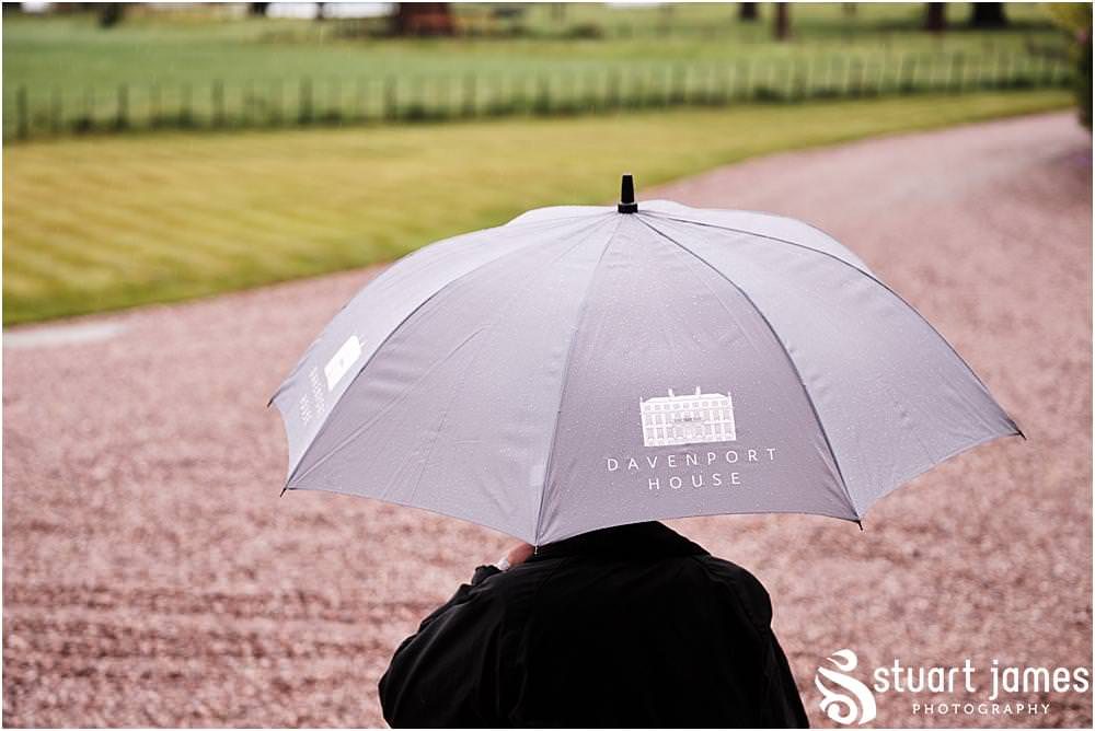 Person stands outside holding a Davenport House umbrella in the rain at Davenport House in Shropshire by Davenport House Wedding Photographers Stuart James