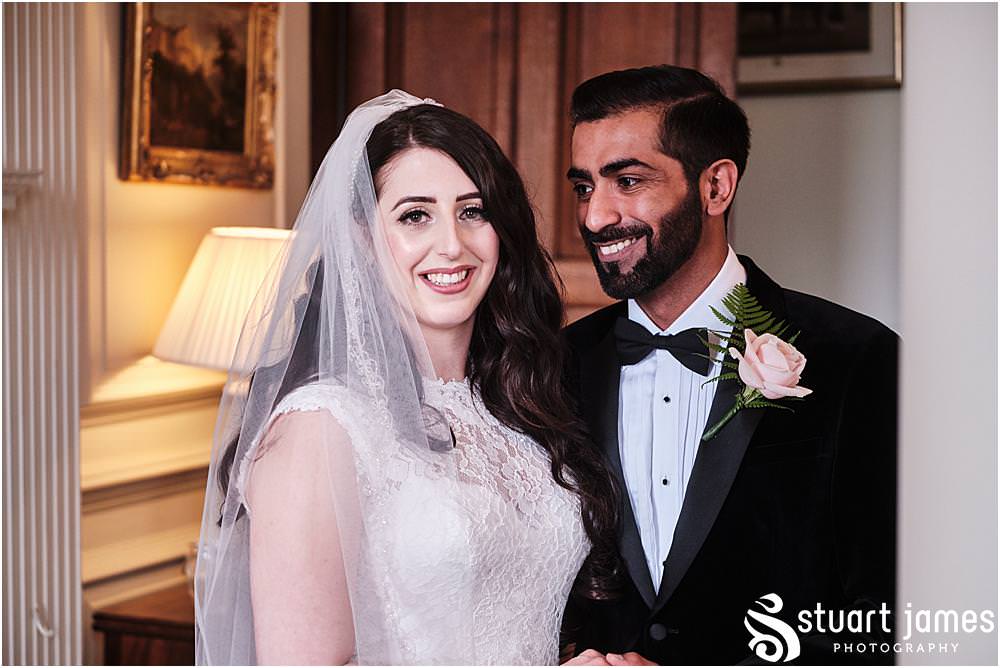 Groom smiles at Bride as she poses for wedding portrait at Davenport House in Shropshire by Davenport House Wedding Photographers Stuart James