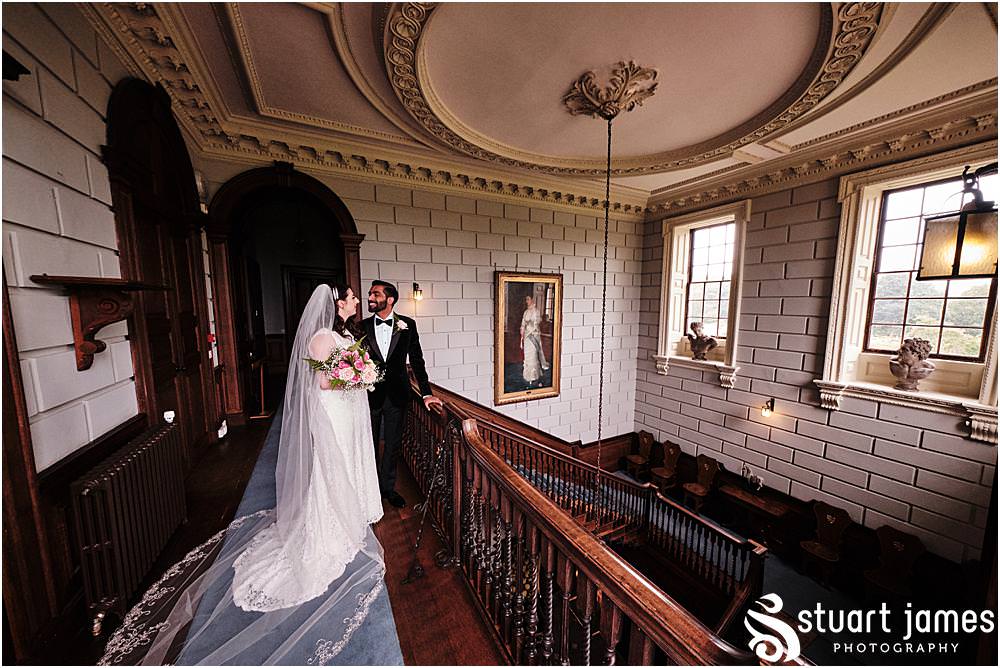Bride and Groom pose for portrait on landing at the top of the dark wood stairs at Davenport House in Shropshire by Davenport House Wedding Photographers Stuart James