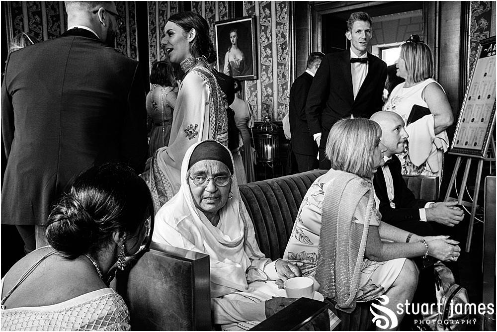Wedding guests sit and talk in room at Davenport House in Shropshire by Davenport House Wedding Photographers Stuart James