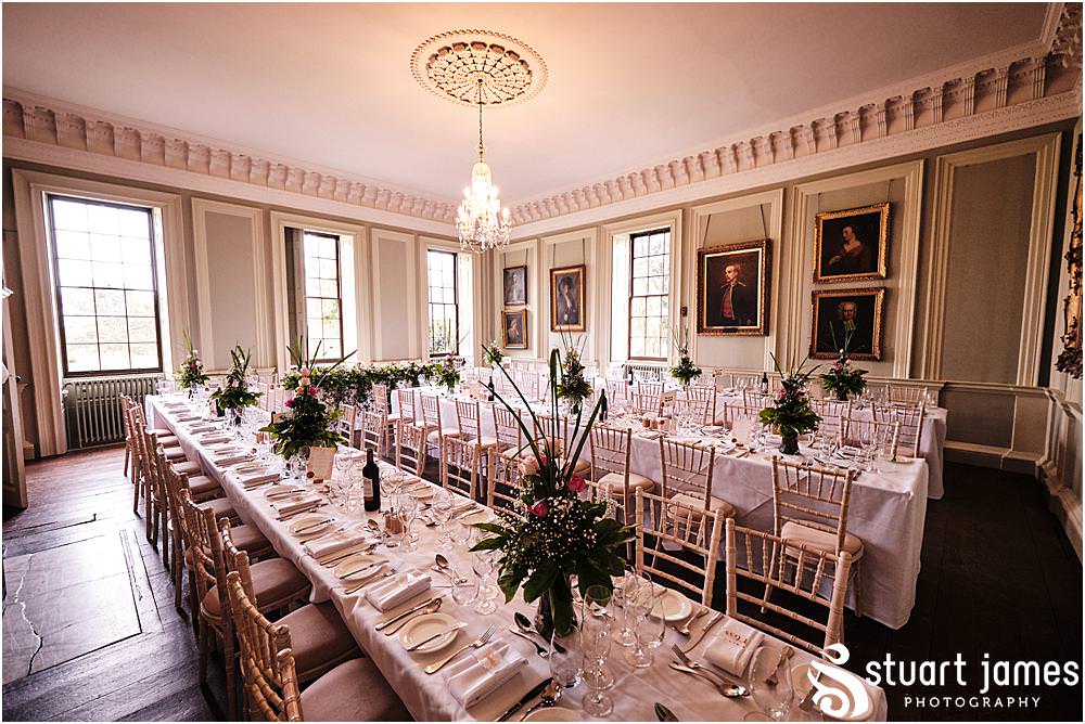 Wedding reception room set up with glassware and pink rose table centre pieces with white linens at Davenport House in Shropshire by Davenport House Wedding Photographers Stuart James