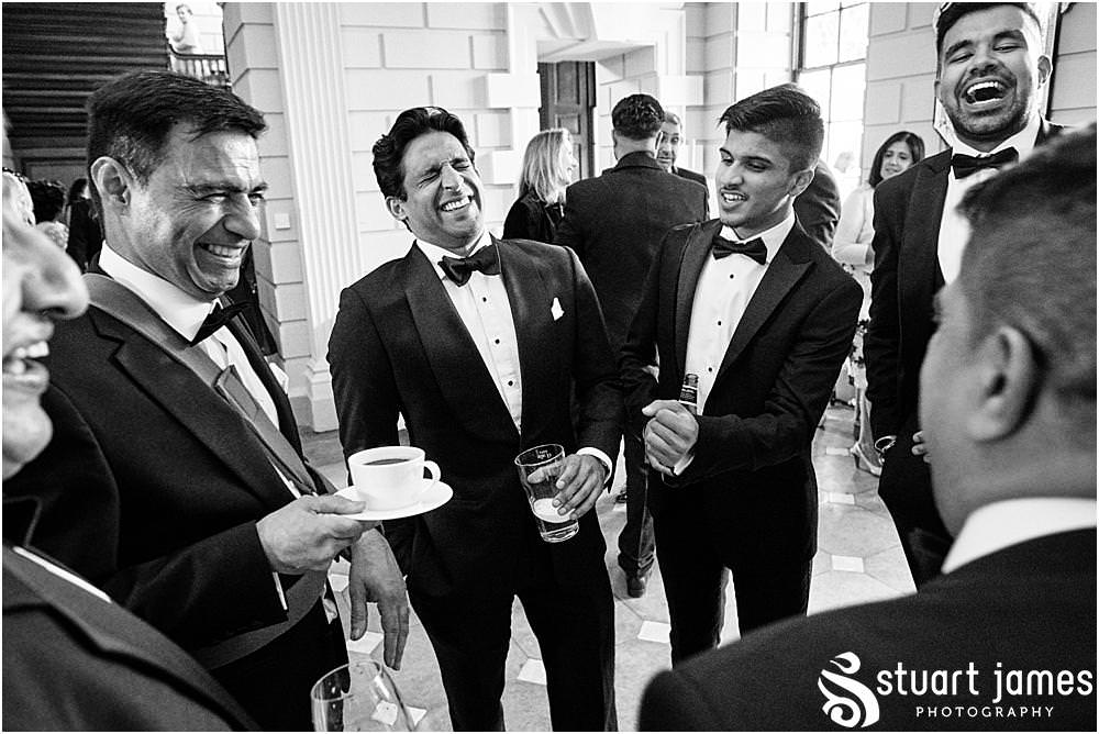 Wedding guests with drinks stand laughing and talking at Davenport House in Shropshire by Davenport House Wedding Photographers Stuart James