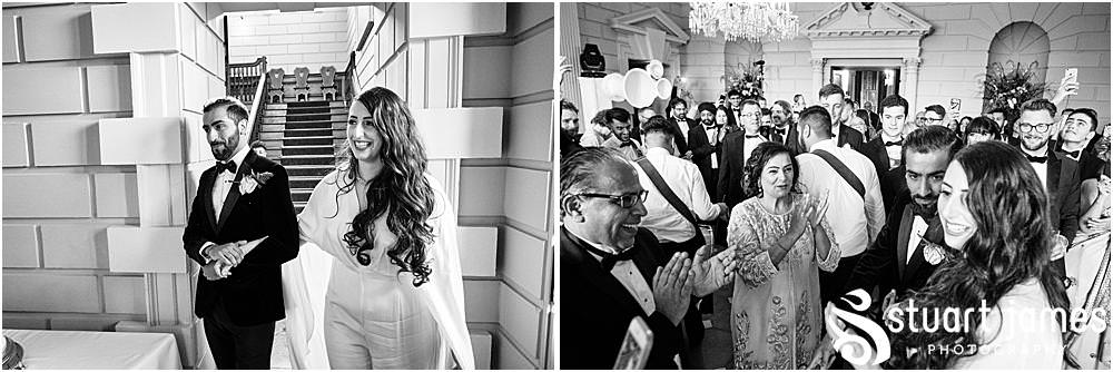 Married couple make entrance down the stairs to the sound of people playing drums at Davenport House in Shropshire by Davenport House Wedding Photographers Stuart James
