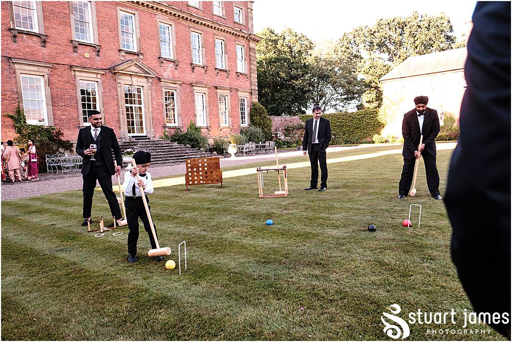 Wedding guests play croquet in the gardens at Davenport House in Shropshire by Davenport House Wedding Photographers Stuart James
