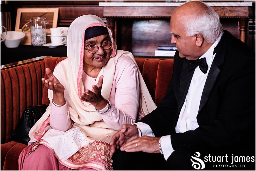 Wedding guests talk inside on sofa at Davenport House in Shropshire by Davenport House Wedding Photographers Stuart James