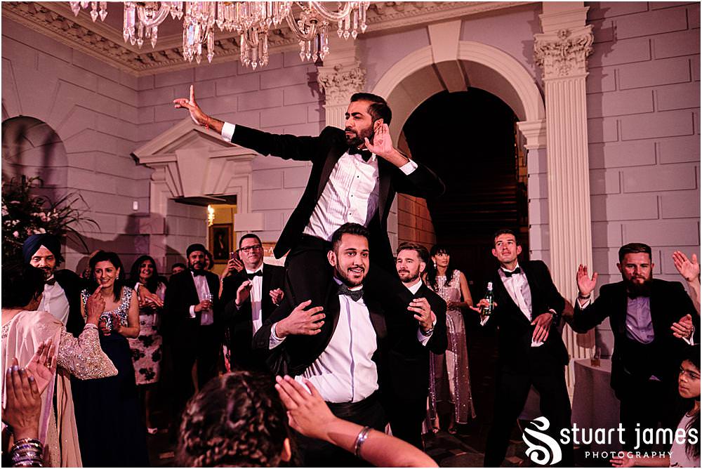 Groom on mans shoulders whilst wedding guests dancing at Davenport House in Shropshire by Davenport House Wedding Photographers Stuart James