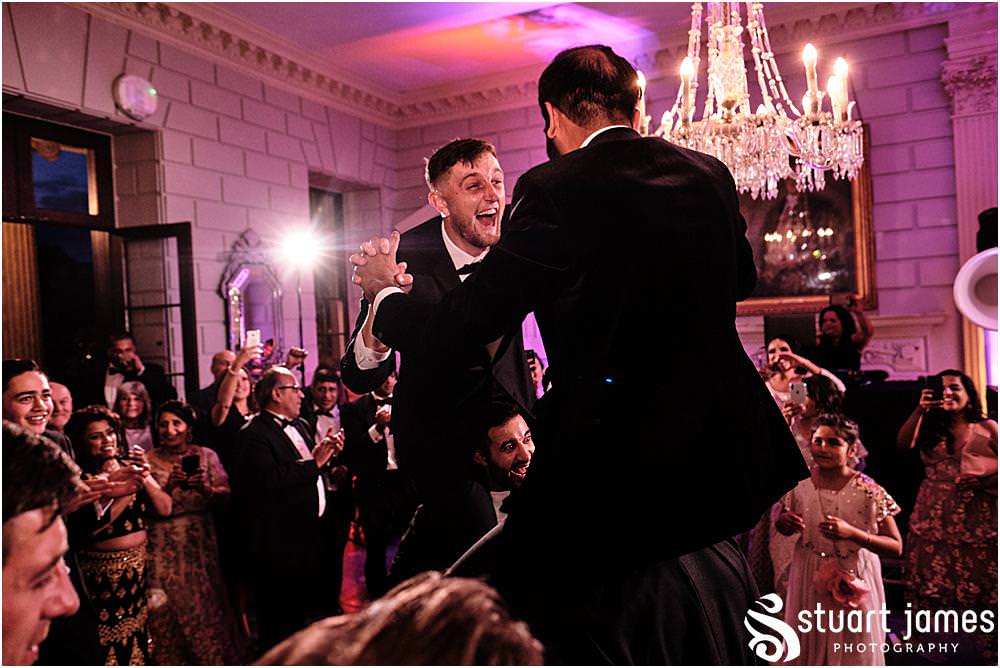 Groom and best man on peoples shoulders whilst wedding guests dancing at Davenport House in Shropshire by Davenport House Wedding Photographers Stuart James