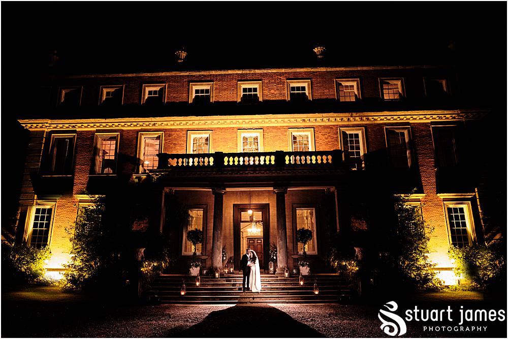 Bride and Groom pose on steps outside Davenport house for a night time portrait at Davenport House in Shropshire by Davenport House Wedding Photographers Stuart James
