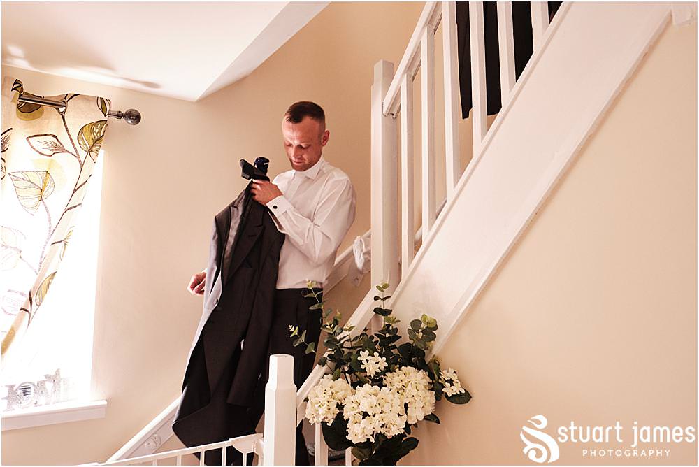 Groom walking down stairs with wedding suit jacket before wedding at The Village Hotel, Walsall, photo by Stuart James Photography