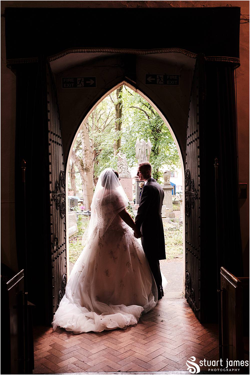 Bride and Groom leave church as a married couple and hold hands at the exit at Holy Trinity Church in Eccleshall, photo by Stuart James Photography at Holy Trinity Church, Eccleshall