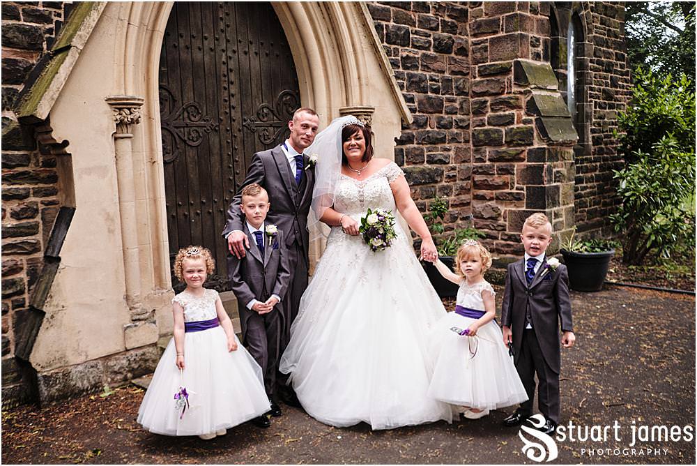 Bride and Groom pose for outside portraits with flower girls and page boys at Holy Trinity Church in Eccleshall, photo by Stuart James Photography at Holy Trinity Church, Eccleshall