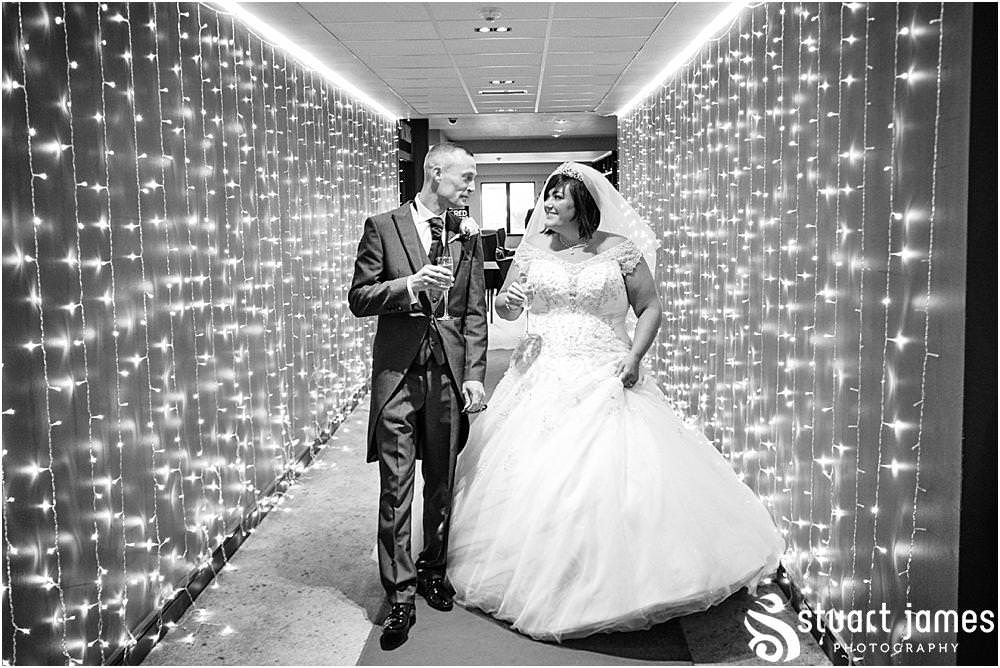 Bride and Groom walk down corridor with drinks at The Village Hotel, Walsall, photo by Stuart James Photography
