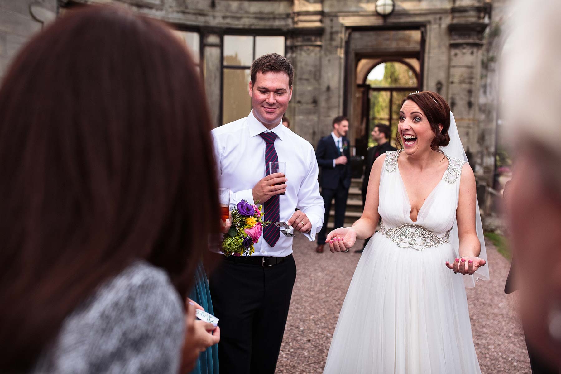 Bride and Groom being entertained by close magician during drinks reception of Sandon Hall in Stafford by Stafford Documentary Wedding Photographer Stuart James
