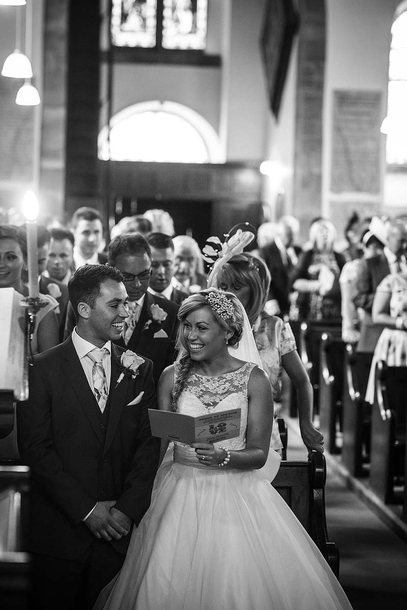 Documentary photograph of Bride and groom exchanging a loving look during ceremony at St Andrews Church at Weston Park in Staffordshire by Reportage Wedding Photographer Stuart James