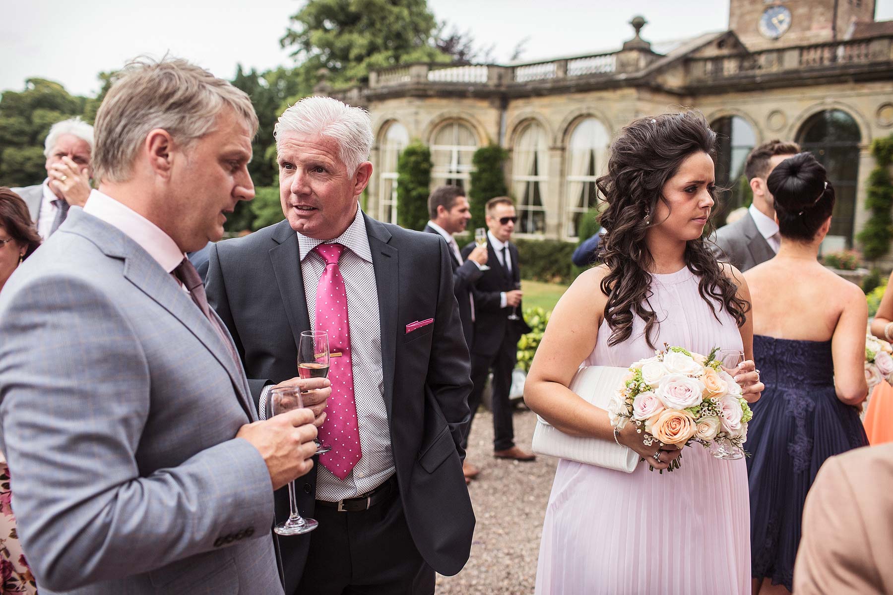 Candid photographs of guests enjoying drinks reception on terrace at Weston Park in Staffordshire by Documentary Wedding Photographer Stuart James